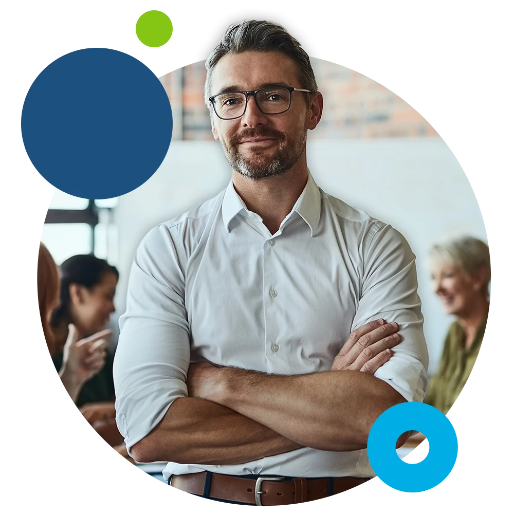 An FBC benefits specialist standing with arms crossed while colleagues meet in the background